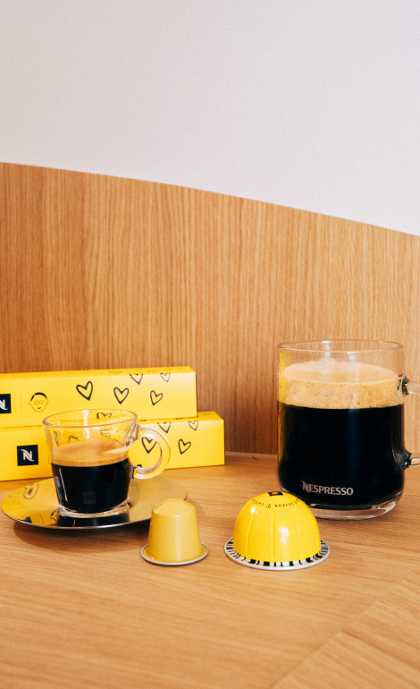 Image de la gamme Nespresso et Café Joyeux avec les paquets de la gamme Original et la gamme Vertuo accompagnés de deux tasses de café et des capsules Original et Vertuo
